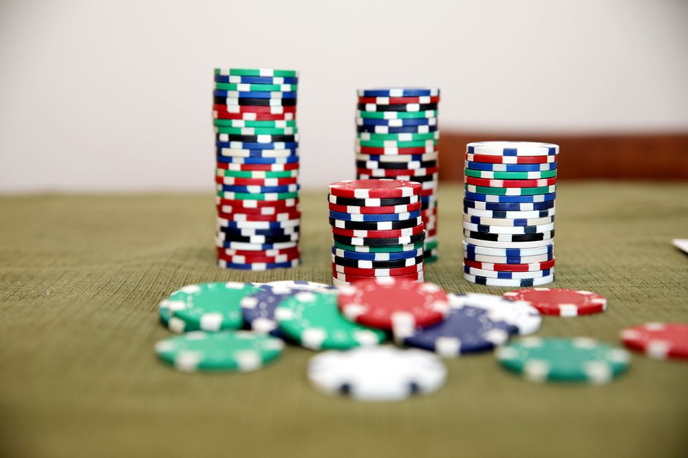 Tumpukan chip poker warna-warni di atas meja hijau