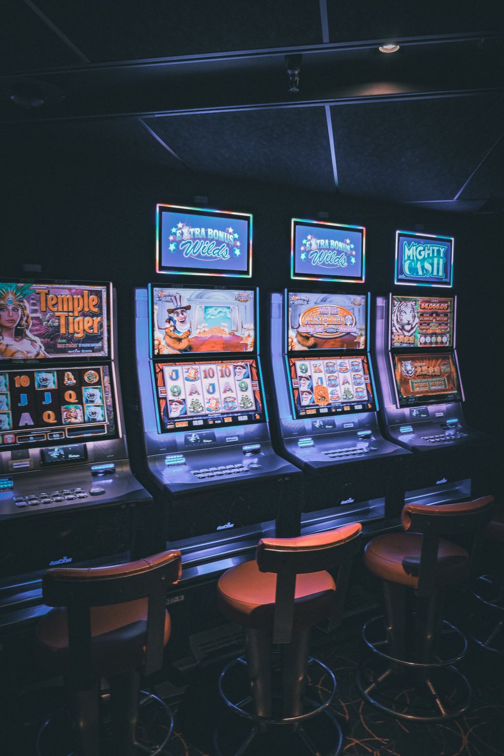Barisan mesin slot dengan layar menyala di lantai kasino